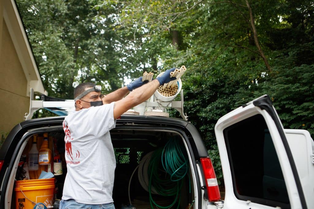 Plumbing Express technician carrying new CPVC pipe into a home